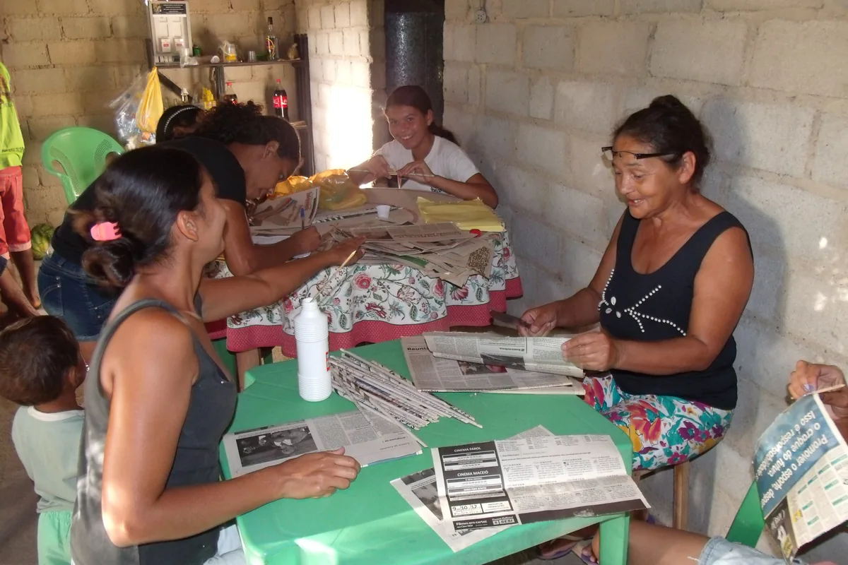 Mulheres do grupo Mão de Fada enrolando tiras de jornal na oficina de artesanato