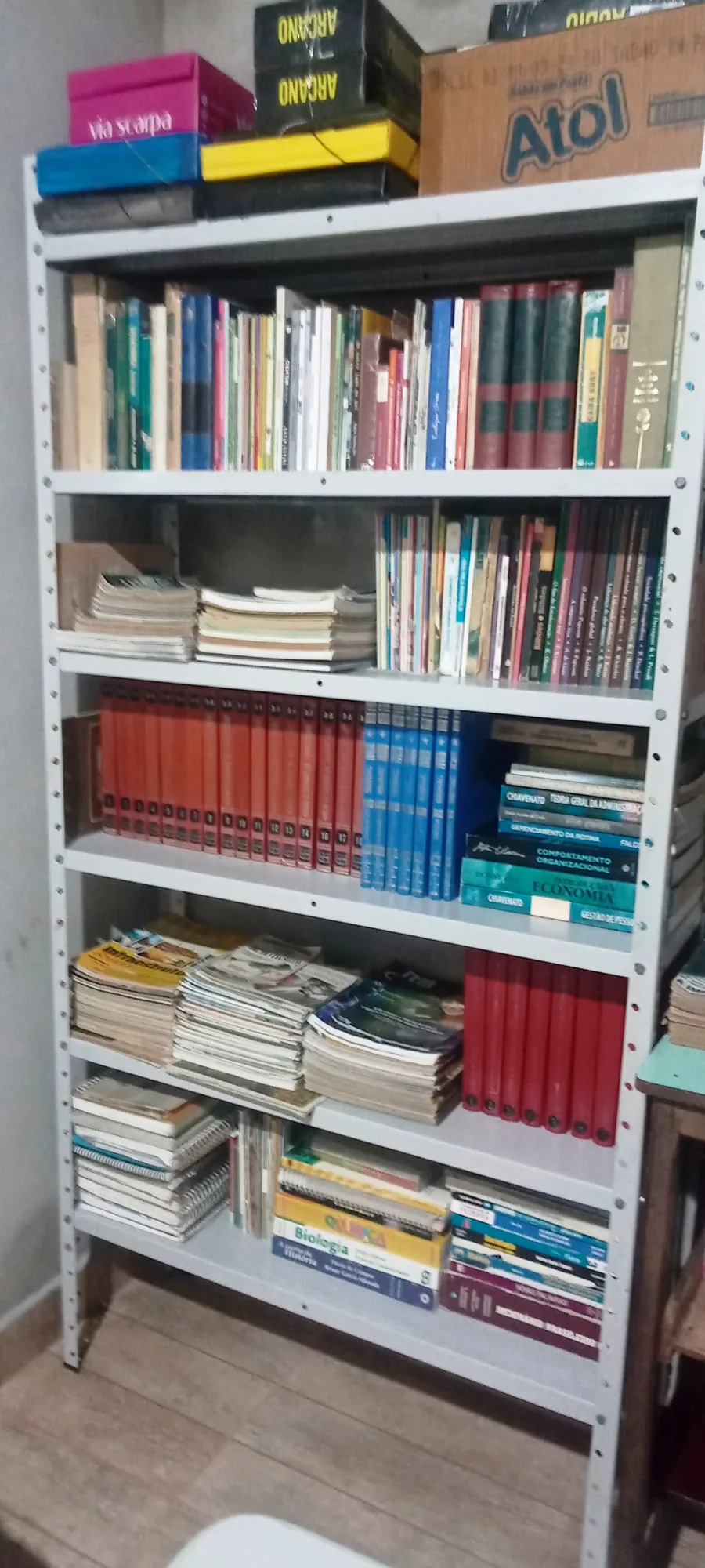 Prateleiras metálicas com livros organizados por assunto na biblioteca comunitária